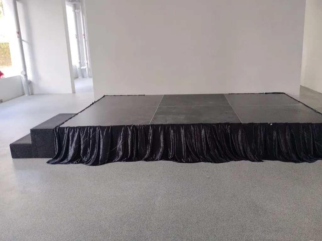 Black platform stage with steps and pleated black skirting at an event space in Singapore