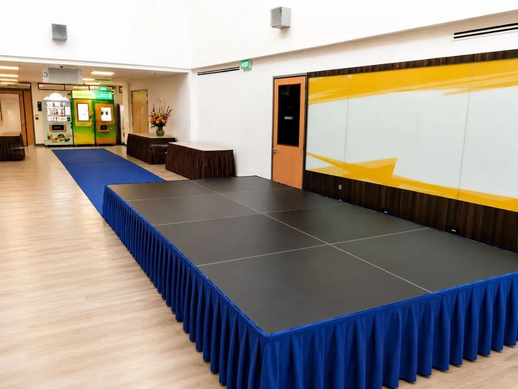 Platform stage with blue skirting and a blue carpet aisle in a Singapore event venue